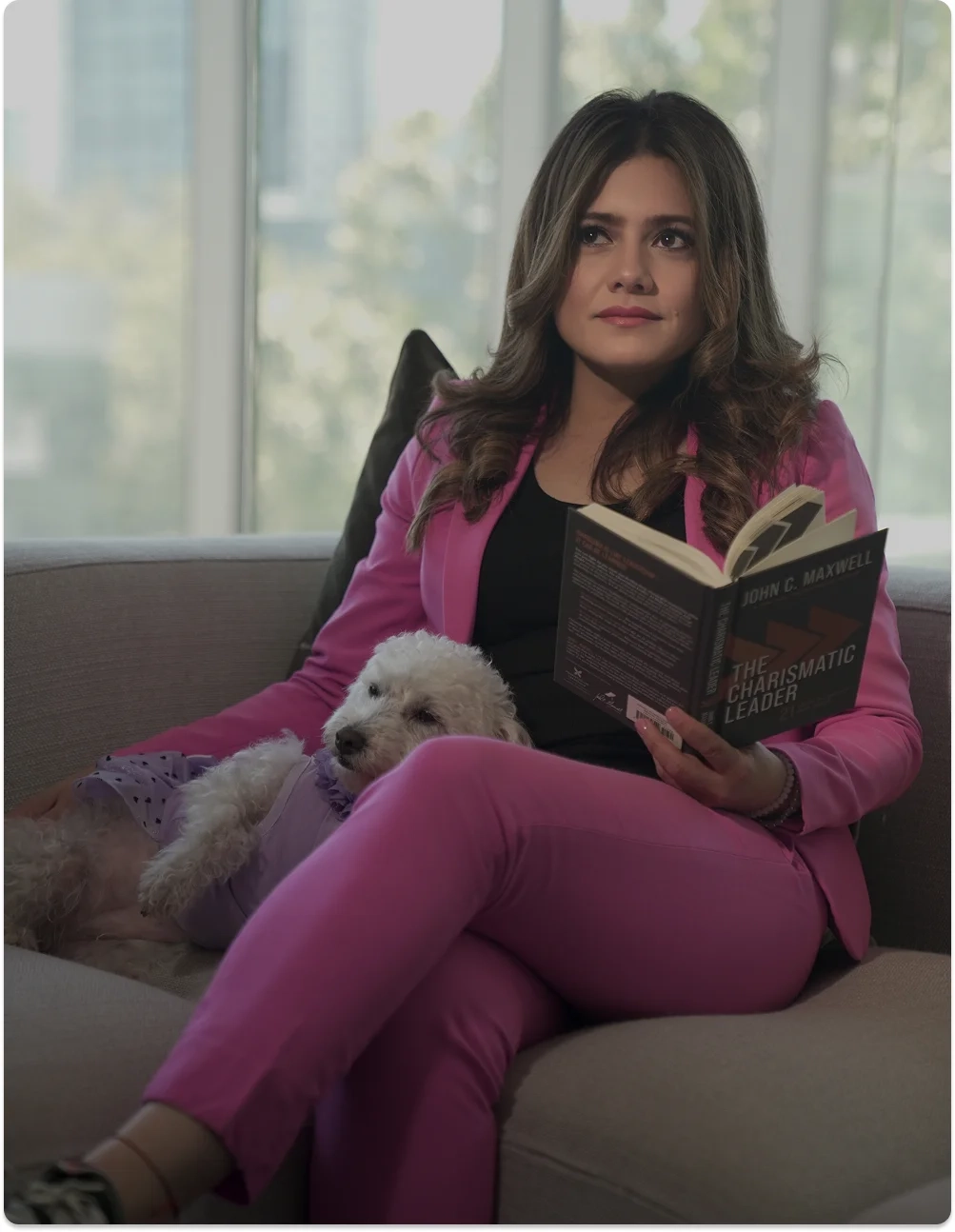 Mujer con traje rosa leyendo un libro junto a su perro, representando la reflexión y el crecimiento personal en la mentoría de Be MEE.