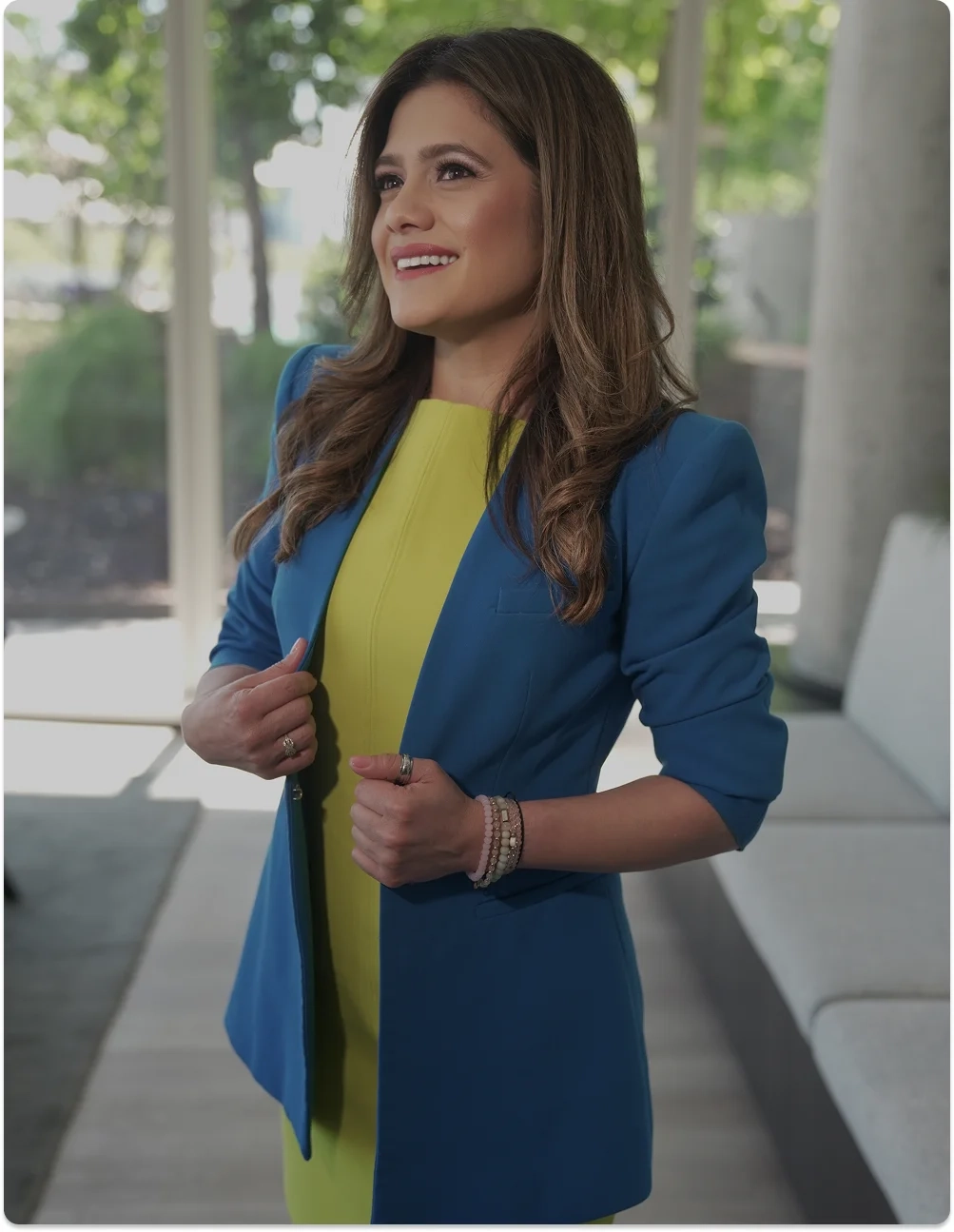 Mujer sonriente con blazer azul y vestido amarillo, representando liderazgo femenino, propósito y mentoría en Be MEE.